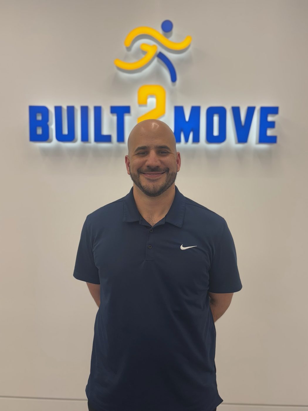 Dr. Armen Rostami, DC, in front of the Built 2 Move logo